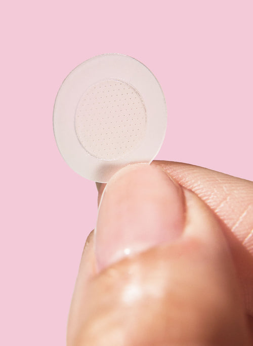 Microneedle pimple patch dot held between fingers
